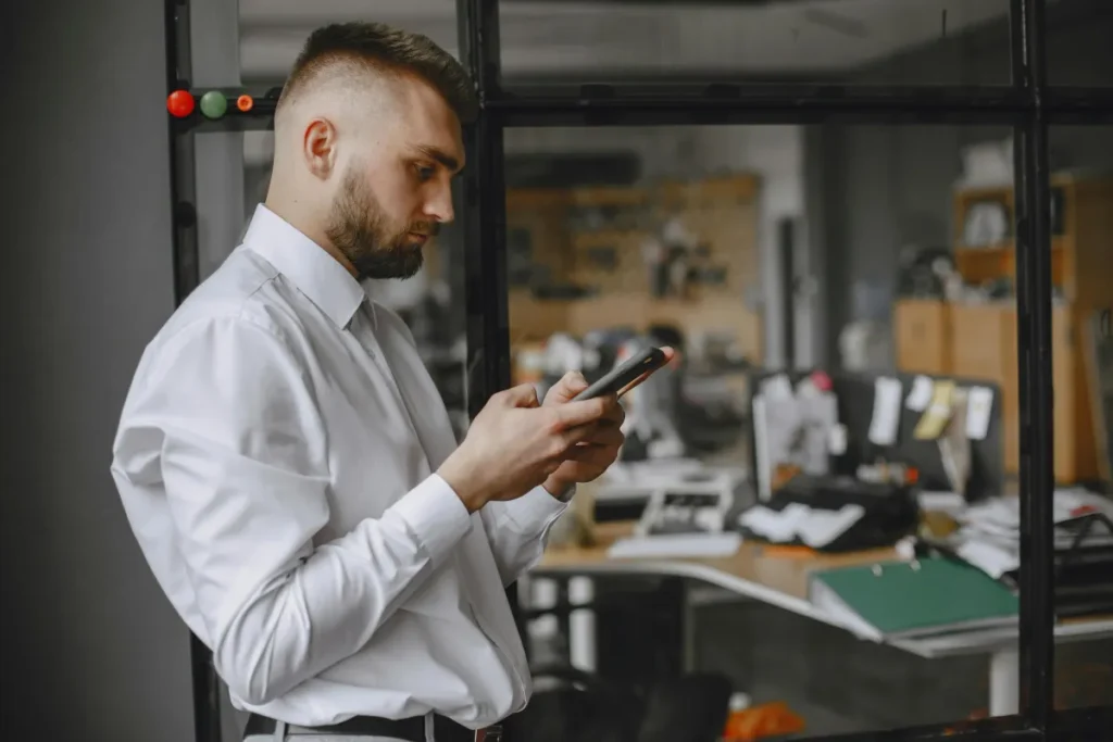 Karyawan menggunakan smartphone di kantor untuk melakukan absensi digital