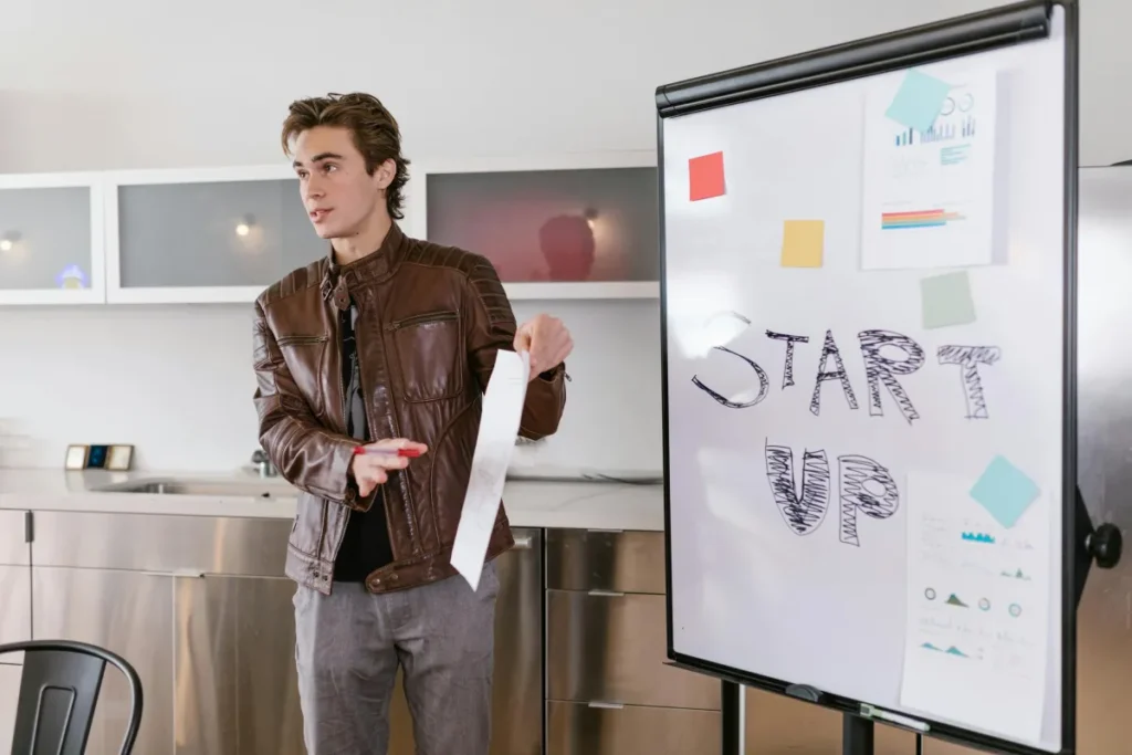Pengusaha muda melakukan pitching presentasi strategi startup di depan papan tulis
